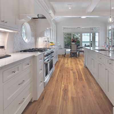 wood look laminate flooring in a large kitchen with white cabinets